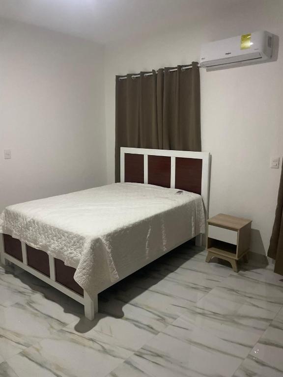 a bedroom with a white bed and a table at res Montesino in San Felipe de Puerto Plata