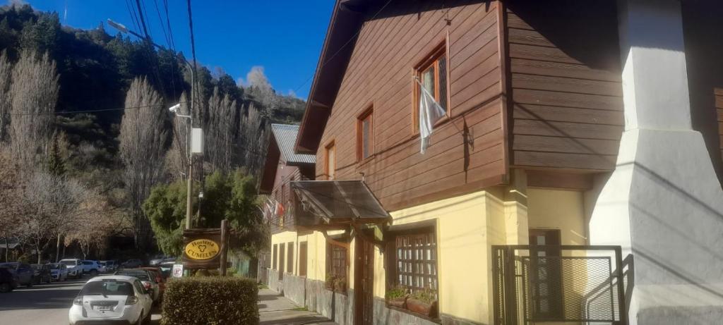 a building with a car parked next to a street at Hosteria Cumelen in San Martín de los Andes