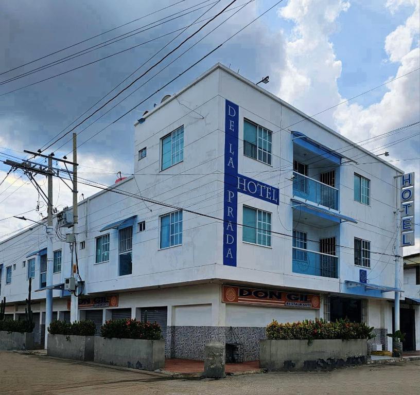 a white building with a blue sign on it at Hotel De La Prada in Maicao