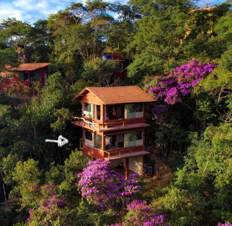 a house in the middle of a forest with flowers at Loft Urucum in Palmeiras