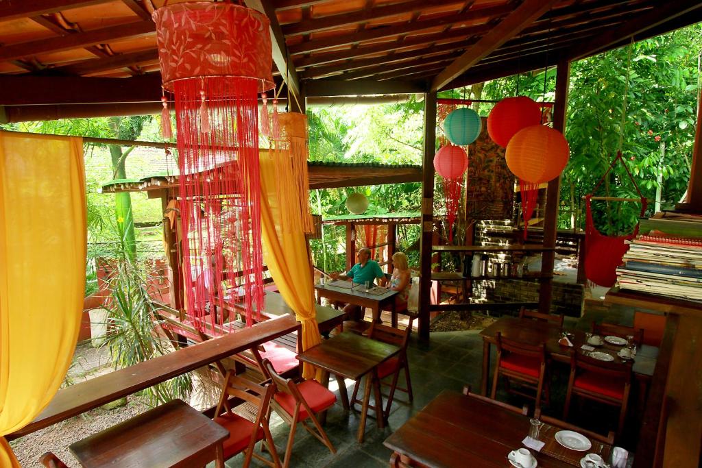 un restaurante con mesas de madera, sillas y globos en Pousada Aquarela, en Morro de São Paulo