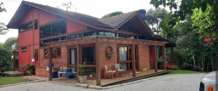 a small red brick house with a porch at Casa Bosque Encantador in Rancho Queimado