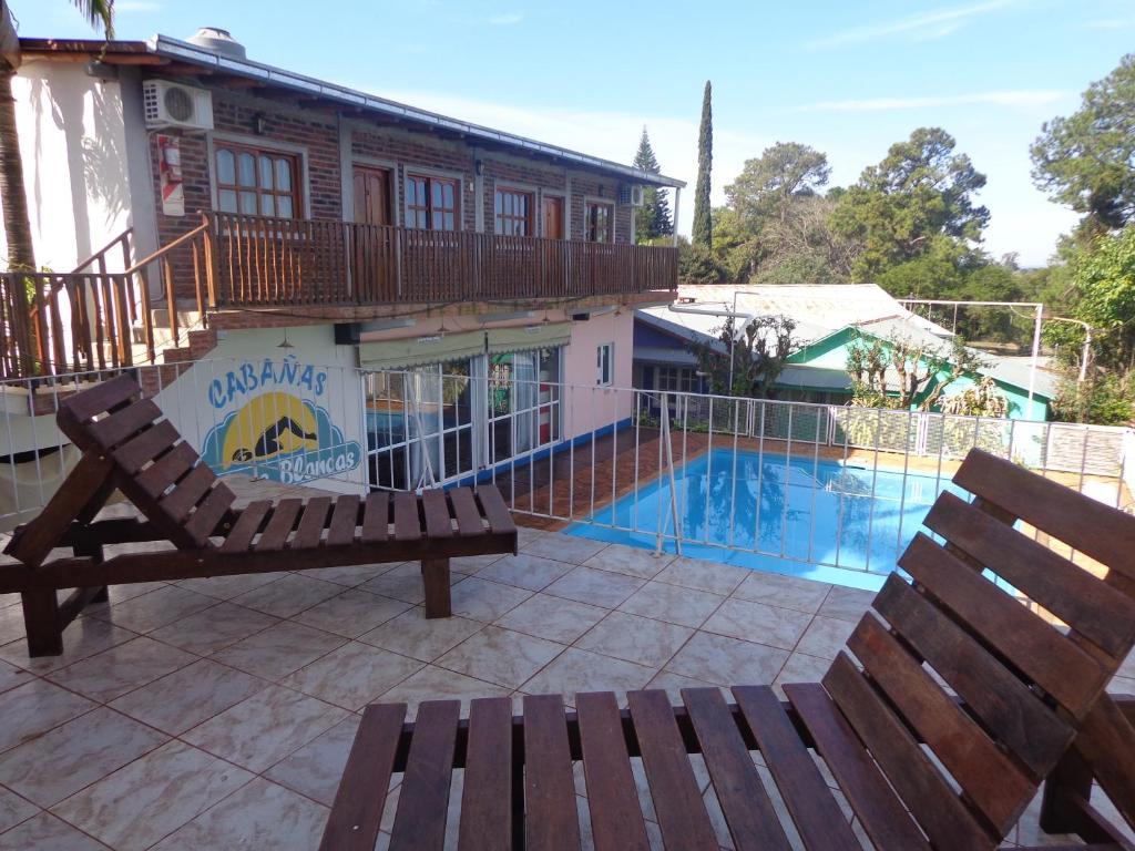 2 bancos de madera situados junto a una piscina en Cabañas Piedras Blancas en Jardín América