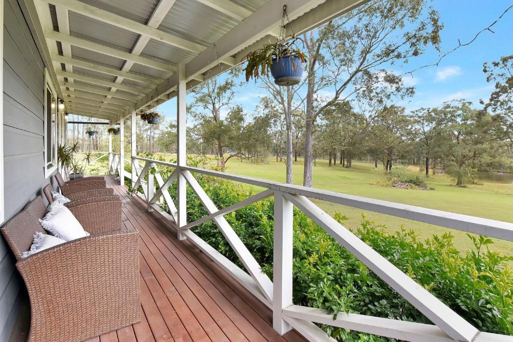 un portico con sedie in vimini e vista su un campo da golf di Windella Cottage a North Rothbury