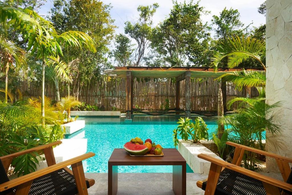 a pool with a table with fruit on it at Relaxing 2BR Condo Omara with Direct Pool Access in Tulum
