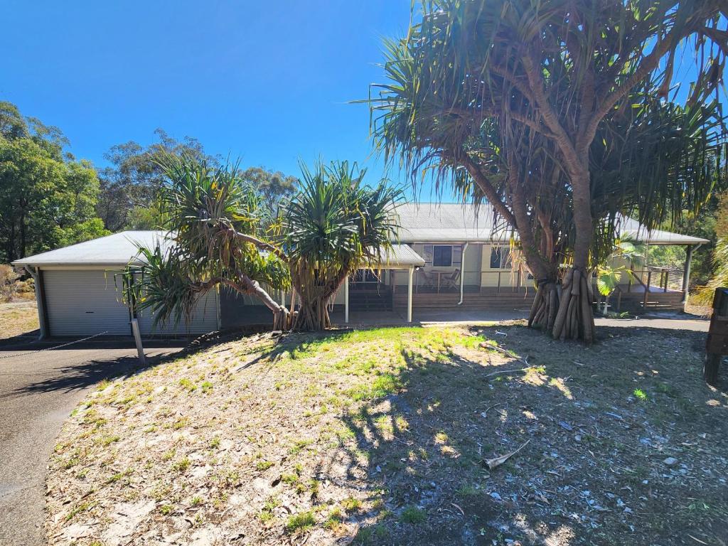 a house with two palm trees in front of it at Avoca Holiday House Fraser Island in Kingfisher Bay