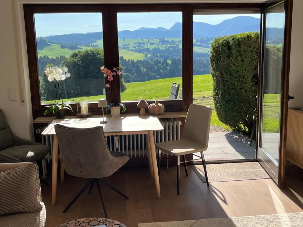 a dining room with a table and chairs and a large window at Neu - Ferienwohnung Allgäuparadies - Traumhafte Aussichten mitten in der Natur des Westallgäus in Oberreute