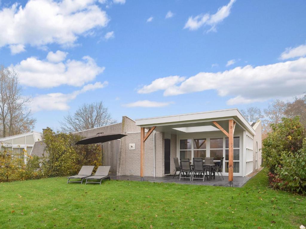 a house with a patio with chairs and tables at Pet-Friendly Getaway in Brouwershaven