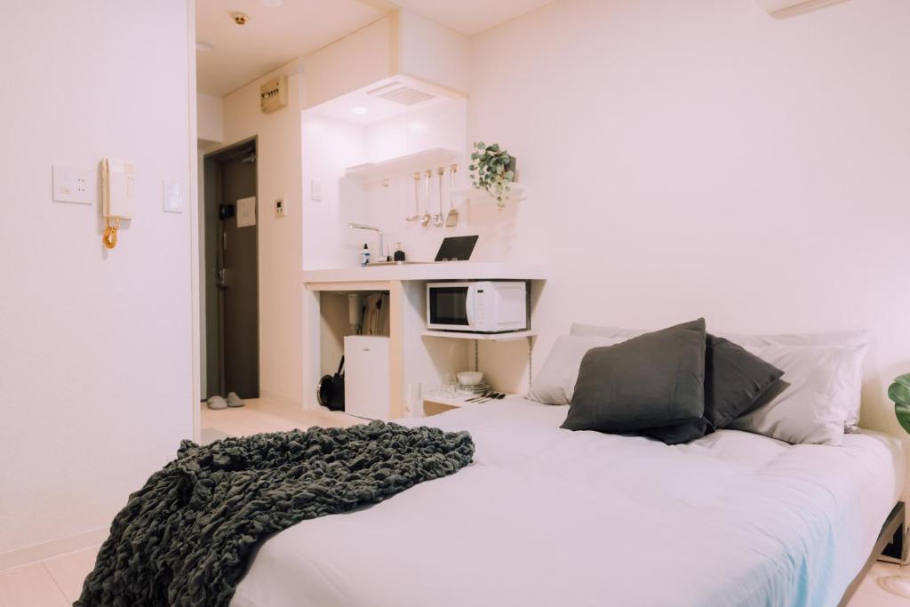 Una cama blanca con una manta negra encima. en Minimalist Loft 3 Namba Compact Studio and 24 hours Gym 01, en Osaka