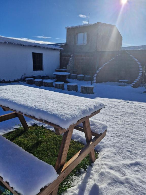 una mesa de picnic cubierta de nieve frente a un edificio en Hospedaje El Quincho, en Gobernador Gregores