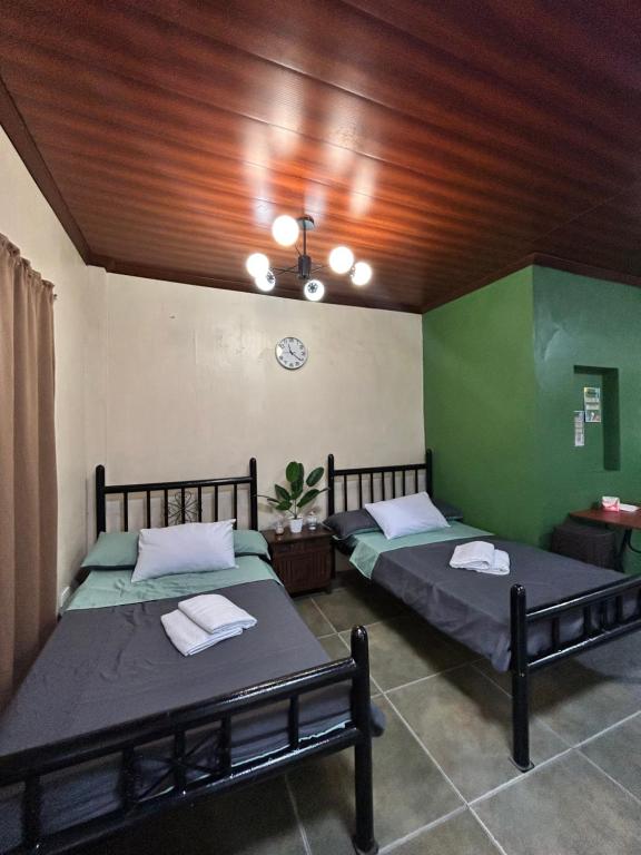 two beds in a room with green walls at Kabbalay Homestay in San Juan