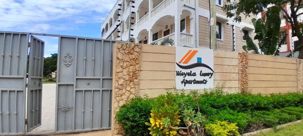 a fence in front of a building with a sign at Beachside 2 bedroom apartment in Diani in Ukunda