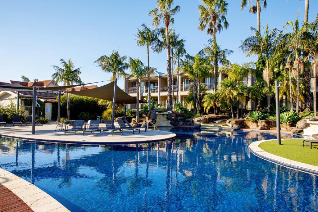 a pool at a resort with palm trees at 39C Cypress in Mulwala