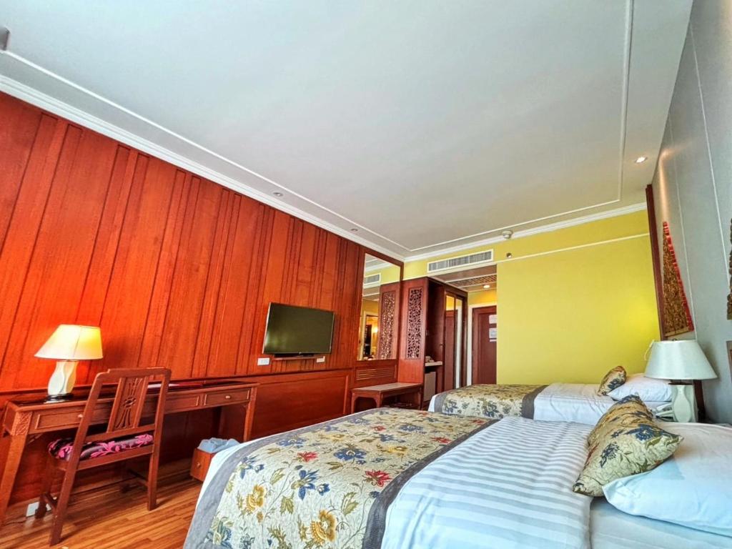 A traditional twin room has two beds, a desk, television and extensive dark wood cabinetry.