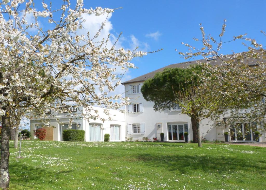 une maison blanche avec des arbres dans la cour dans l'établissement Logis Hôtel Restaurant des Châteaux, à Azay-le-Rideau