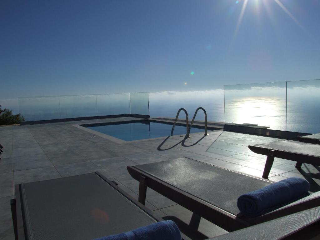 eine Terrasse mit einem Pool mit einem Tisch und einem Tisch in der Unterkunft Kampaki Stone Houses in Agios Nikitas