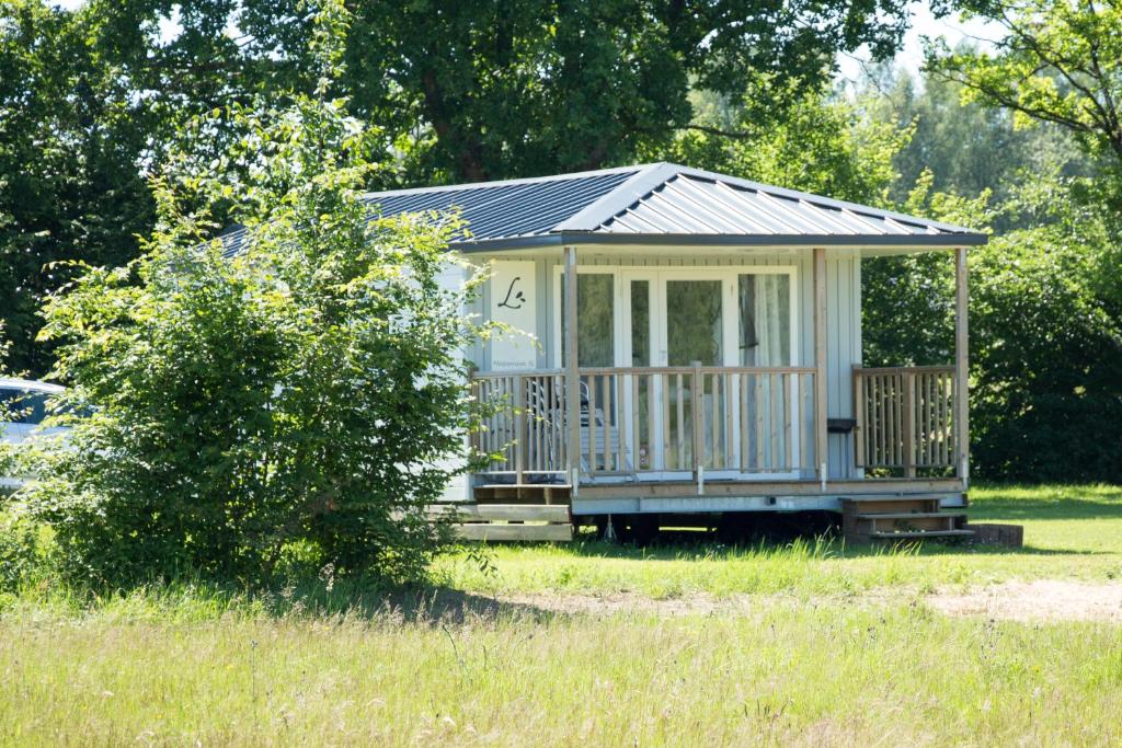 una piccola cabina bianca con portico in un campo di Campingplatz Jungferweiher a Ulmen