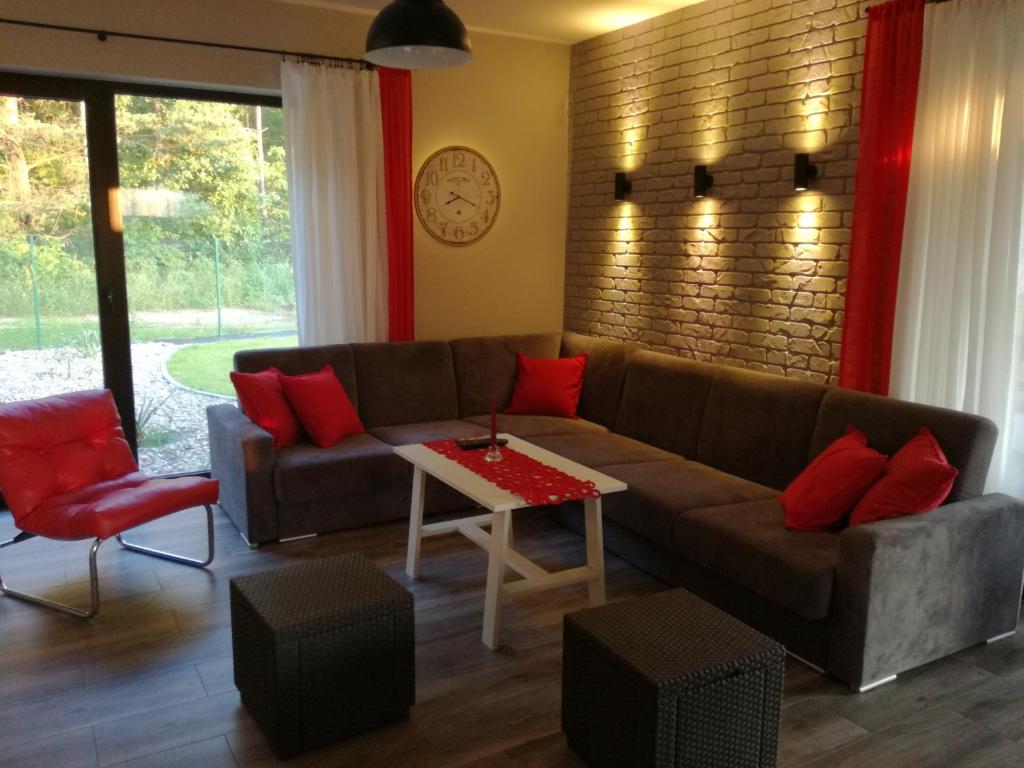 a living room with a brown couch and red pillows at Cudodomek SPA w Mrozach Wielkich koło Ełku in Ełk