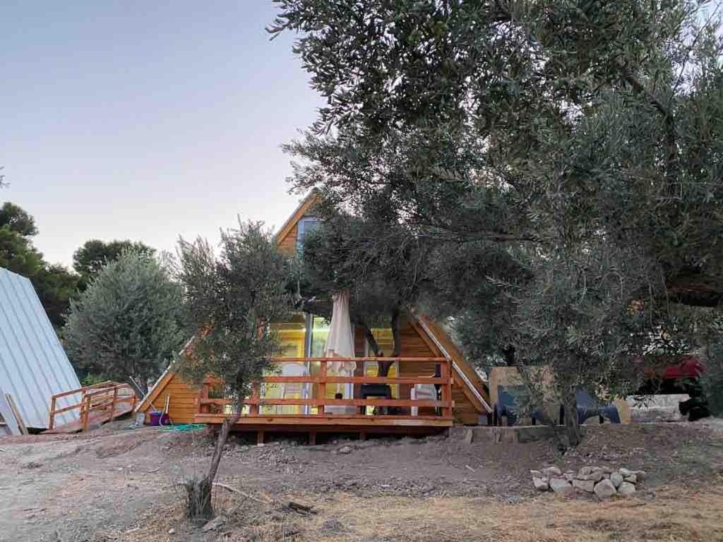 a house sitting on top of a field next to a tree at Bungalow-8 in Karaburun Boyabağ Bay in Karaburun
