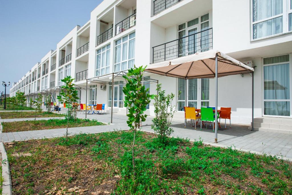 a building with a table and chairs and an umbrella at Gold Bugaz Black Sea Hotel Group in Gribovka