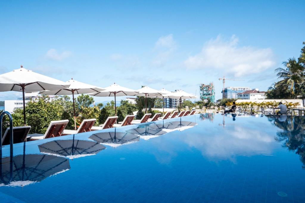 a swimming pool with chairs and umbrellas at Onederz Sihanoukville - 10 mins walk from the Tourism Pier in Sihanoukville