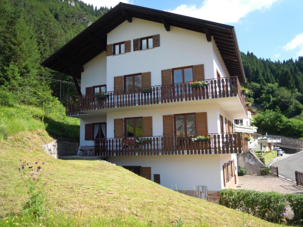 a white house with a balcony on a hill at Appartamenti Rosenberger in Molveno