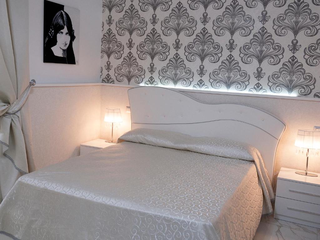 um quarto com uma cama branca e 2 candeeiros em La Dimora Del Marchese em Catânia