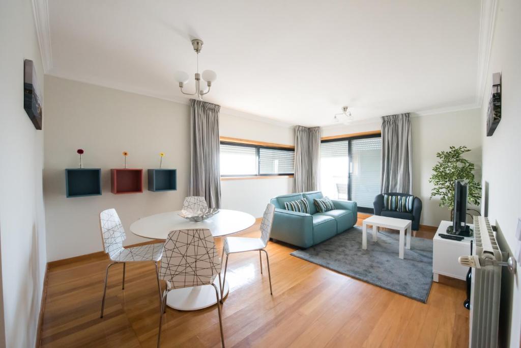 een woonkamer met een tafel en een blauwe bank bij Porto RiverSea Quay Apartment in Matosinhos