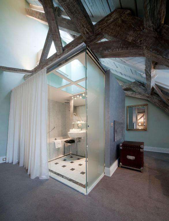 a bathroom with a glass shower and a sink at Hotel Le Place d'Armes - Relais & Châteaux in Luxembourg