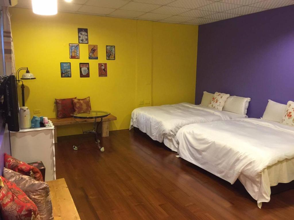 two beds in a room with yellow and purple walls at Pottery B&amp;B in Jiaoxi