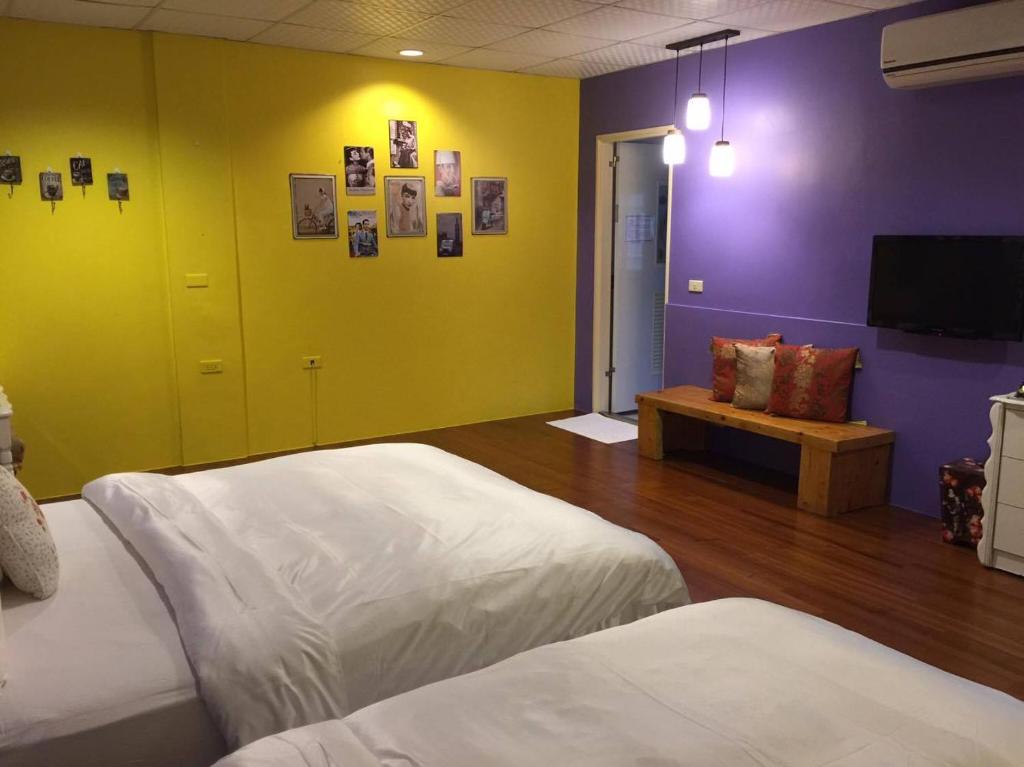 a bedroom with two beds and a purple and yellow wall at Pottery B&amp;B in Jiaoxi