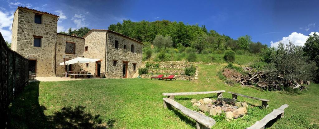 a stone building with a yard with a table at Le Case Della Buca Agriturismo ed Agricampeggio in Seggiano