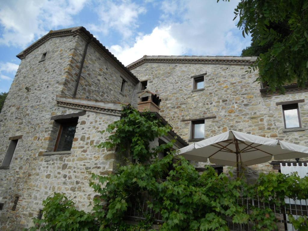 a large stone building with an umbrella in front of it at Il Castello in Monte Cerignone