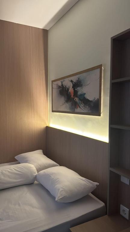 a bedroom with a bed with a painting on the wall at BEE ROOM Sanur in Sanur