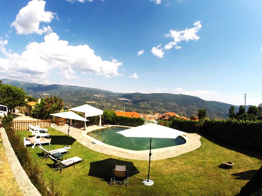 a swimming pool with chairs and an umbrella at Casa Rural El Regajo Valle del Jerte in El Torno