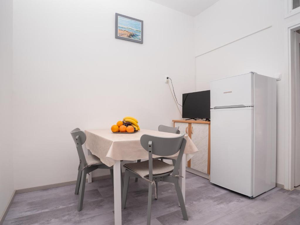 a kitchen with a table with chairs and a white refrigerator at Apartment Ana in Pula