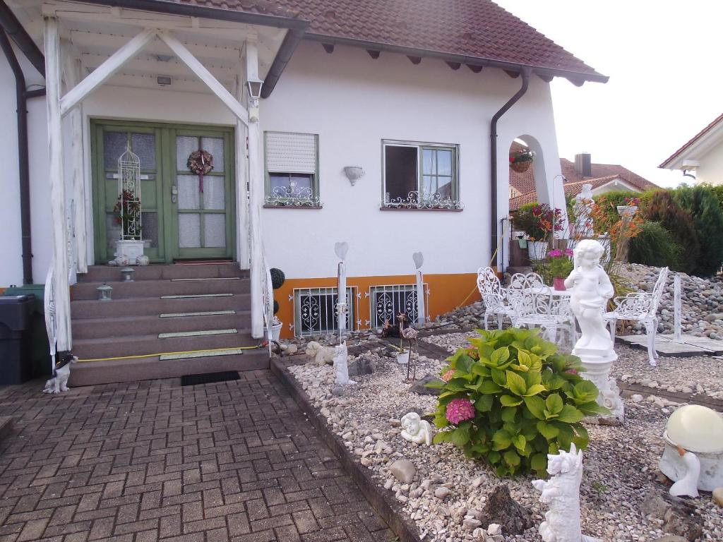 Casa blanca con porche delantero y sillas en Gästehaus Baur, en Kappel-Grafenhausen