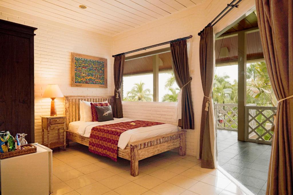 a bedroom with a bed and a large window at Tauch Terminal Resort Tulamben & Spa in Tulamben