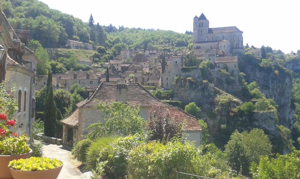 uma aldeia numa colina com um castelo ao fundo em Charme, jardin et vue panoramique en plein coeur de St-Cirq em Saint-Cirq-Lapopie