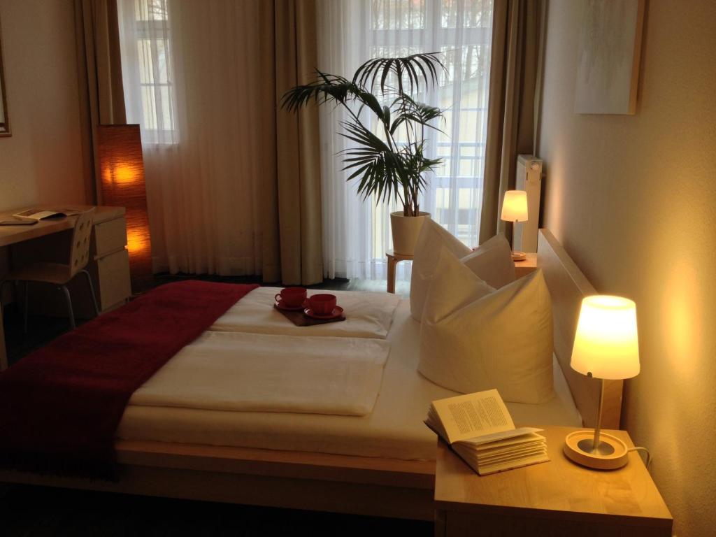 una camera d'albergo con letto e tavolo con lampada di Apartmenthaus Feuerbach a Lipsia