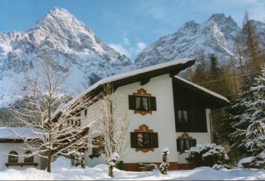 a house in the snow with mountains in the background at Gästehaus Sylvia in Biberwier