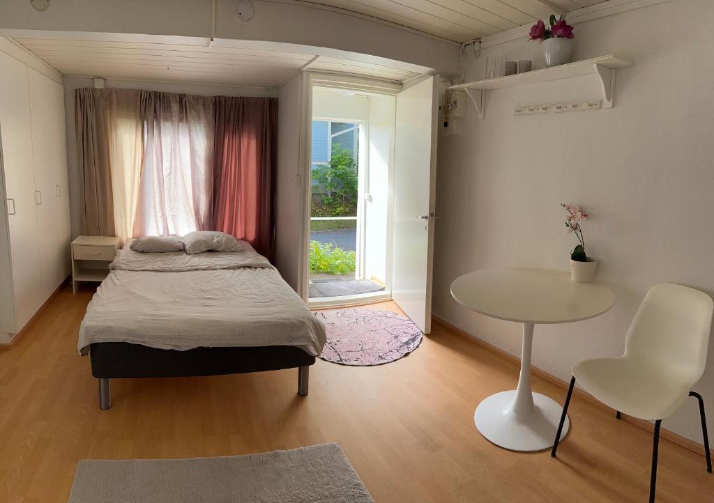 a bedroom with a bed and a table and a window at Wooden house studio 1 km from river Turku in Turku