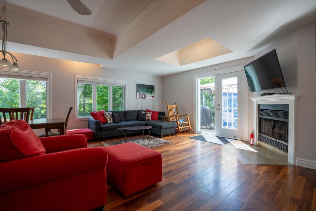 a living room with a red couch and a fireplace at Absolute comfort with SPA - Le Havre du Confort in Mille-Isles