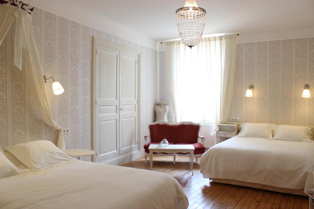 a bedroom with two beds and a chair and a window at Hôtel De La Providence in Égliseneuve-dʼEntraigues