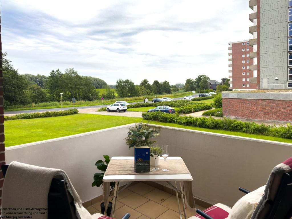 a balcony with a table and a view of a street at FeWo Dünenrose - Horumersiel in Horumersiel