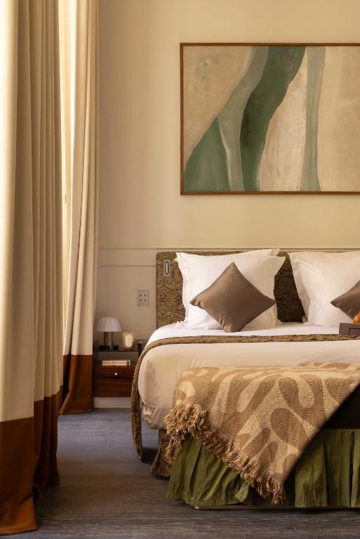 a bedroom with a bed with a painting above it at Hotel Palais Bourbon in Paris