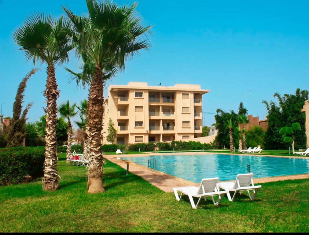 a resort with two palm trees and a swimming pool at Résidence Coralia, piscine, fibre obtique, Parking gratuit in Marrakech
