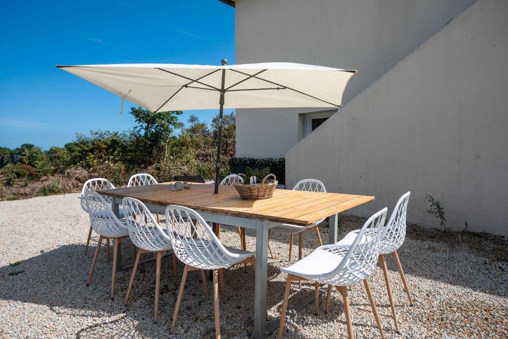 a wooden table with chairs and an umbrella at Villa Les Agapanthes in Paimpol