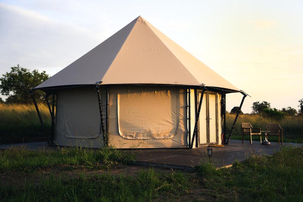 a large tent with a chair in a field at Malaika Ndutu Luxury Camp in Sinoni