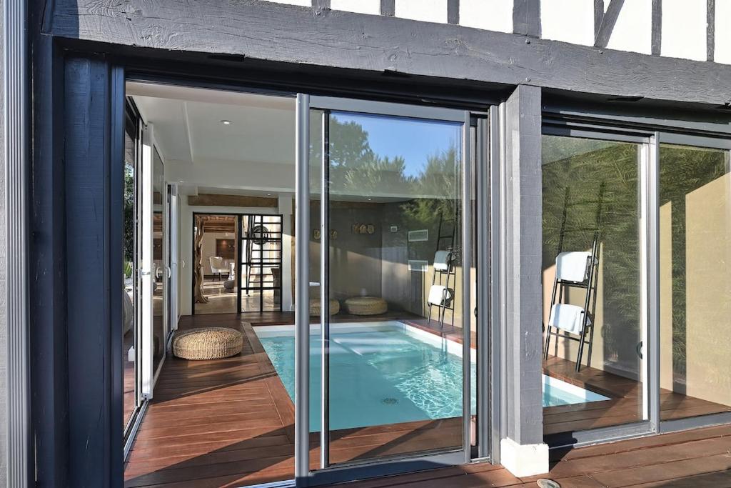 a house with a swimming pool with sliding glass doors at Le Jardin des Hespérides - Piscine intérieure, Jacuzzi et Sauna in Fourmetot